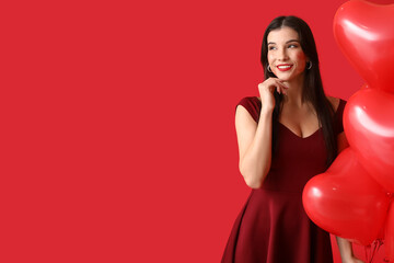 Wall Mural - Beautiful young woman with kiss marks on her face and heart shaped air balloons on red background