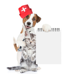 Poster - Funny jack russell terrier dressed like a doctor with stethoscope on his neck hugs tiny kitten and shows empty notebook. isolated on white background