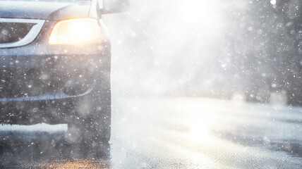 Wall Mural - snowfall, car, background in a snowstorm with a copy of the space, the headlights of an oncoming car through a thick snowfall, winter view on the highway, headlight light