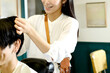 © koumaru - 男性客のヘアスタイリングをするアジア人の女性美容師