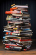 A stack of books, magazines and newspapers sitting on top of a wooden table.