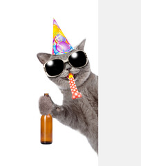 Poster - Happy Cat wearing sunglasses and birthday cap blows in party horn, holds bottle of beer and looks from behind empty white banner. isolated on white background
