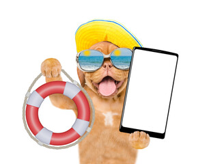 Poster - Happy mastiff puppy wearing summer hat and mirrored sunglasses shows lifebuoy and holds big smartphone with white blank screen in it paw. Isolated on white background