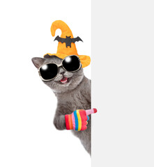 Poster - Happy cat wearing hat for halloween and sunglasses points away on empty white banner. isolated on white background