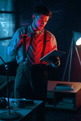 Poster - Young serious male analyst or director of business company with tablet looking through data in electronic document in dark office
