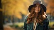 © Suleyman - On a chilly day, a serene girl wearing a blue coat, green hat, and coat closes her eyes as she enjoys a sunny day in an autumn park with a blurry background.