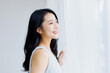 © Paylessimages - 朝、窓辺に立つ女性