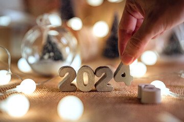 Wall Mural - hands of woman put 2024 numbers on decorated table, merry christmas and happy new year!