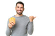 Young caucasian man holding fried chips over isolated chroma key background pointing to the side to present a product