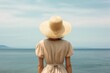 © Veve - Back view of a woman with a hat looking at the sea