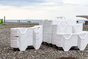 Poster - travel to Georgia - stacks of plastic beach chairs on pebble sea beach in Batumi city on cloudy autumn day