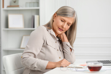 Wall Mural - Woman suffering from neck pain at workplace in room