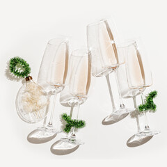 Wall Mural - Minimal New Year flat lay with white wine in champagne glasses, Christmas green tinsel, Christmas glass ball as decor. Holiday aesthetic still life photo, top view wineglass at sunlight, shadow