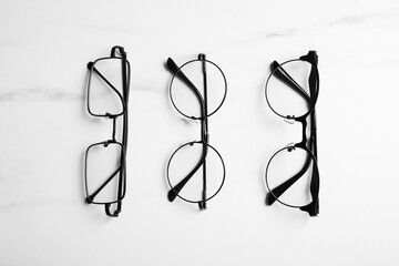 Poster - Glasses in stylish frames on white marble table, flat lay