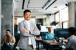 © Drazen - Portrait of confident Asian entrepreneur with arms crossed in office looking at camera.