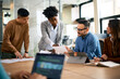 © Drazen - Multiracial business team analyzing reports on meeting in office.