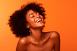 © Enrique - a black woman smiles in the studio on orange background. happy model