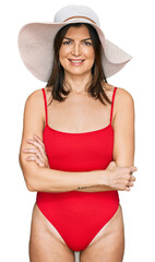 Wall Mural - Beautiful brunette woman wearing swimsuit and summer hat happy face smiling with crossed arms looking at the camera. positive person.