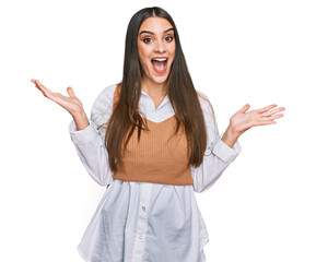 Wall Mural - Young beautiful woman wearing casual white shirt celebrating victory with happy smile and winner expression with raised hands