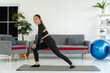 Asian Woman Standing Stretching Legs on Yoga Mat in Living Room