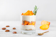 Trifle in a glass with persimmon, rosemary, pecan, whipped cream and biscuit. Healthy food, vegan, sugar, gluten and lactose free.