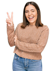 Canvas Print - Young beautiful woman wearing casual clothes smiling with happy face winking at the camera doing victory sign with fingers. number two.