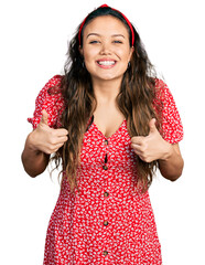 Wall Mural - Young hispanic girl wearing casual clothes success sign doing positive gesture with hand, thumbs up smiling and happy. cheerful expression and winner gesture.