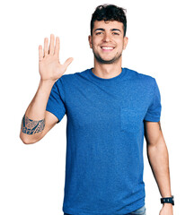 Poster - Young hispanic man wearing casual t shirt showing and pointing up with fingers number five while smiling confident and happy.