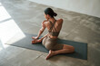 © standret - Conception of wellbeing and health care. Rear view of young woman on yoga mat indoors