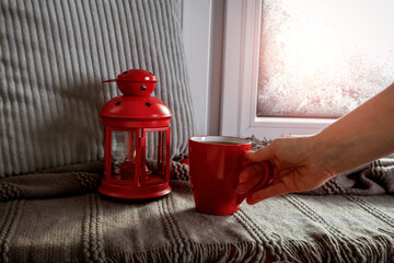 Poster - Red chrismtas lamp on window sill and empty space for your decoration. Cold december day and new year composition. Woman hands. Snow and frost decoration. 