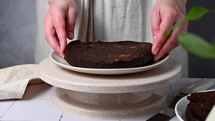 Wall Mural - Cooking chocolate fruit cake, adding a layer of sponge cake on rotating cake stand.