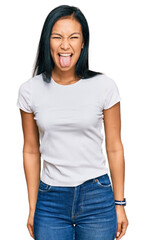 Poster - Beautiful hispanic woman wearing casual white tshirt sticking tongue out happy with funny expression. emotion concept.