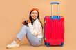 © anon - Tourist asian woman in casual clothes hat hold suitcase using mobile cell phone sit isolated on colour background Passenger travel abroad weekends .