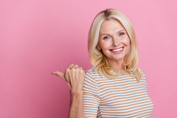 Poster - Photo of cheerful person with blond hairstyle dressed striped t-shirt indicating at discount empty space isolated on pink color background