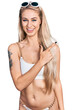 © Krakenimages.com - Beautiful young blonde woman wearing bikini cheerful with a smile of face pointing with hand and finger up to the side with happy and natural expression on face