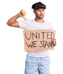 Sticker - Young hispanic man holding united we stand banner with angry face, negative sign showing dislike with thumbs down, rejection concept