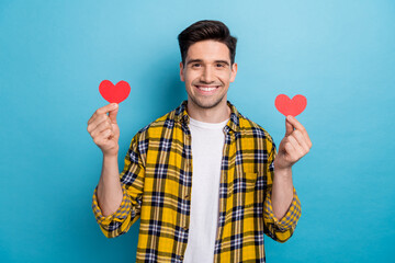 Canvas Print - Photo of handsome boyfriend in casual trendy garment hold two red handmade postcards heart figure isolated on blue color background