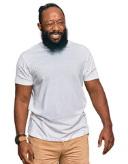 Poster - Young african american man wearing casual white tshirt winking looking at the camera with sexy expression, cheerful and happy face.