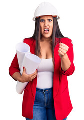 Poster - Young beautiful brunette woman wearing hardhat holding architect blueprint annoyed and frustrated shouting with anger, yelling crazy with anger and hand raised