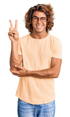 Young hispanic man wearing casual clothes and glasses smiling with happy face winking at the camera doing victory sign. number two.