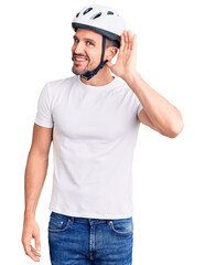 Canvas Print - Young handsome man wearing bike helmet smiling with hand over ear listening an hearing to rumor or gossip. deafness concept.