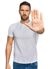 Poster - Handsome man with beard wearing casual white t shirt doing stop sing with palm of the hand. warning expression with negative and serious gesture on the face.