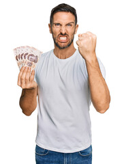 Sticker - Handsome man with beard holding 50 mexican pesos banknotes annoyed and frustrated shouting with anger, yelling crazy with anger and hand raised