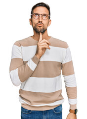 Wall Mural - Handsome man with beard wearing casual clothes and glasses thinking concentrated about doubt with finger on chin and looking up wondering