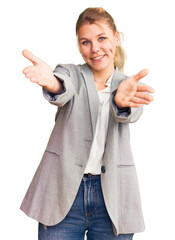 Wall Mural - Young beautiful blonde woman wearing elegant jacket looking at the camera smiling with open arms for hug. cheerful expression embracing happiness.