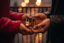 Close Up Of Couple's Hands Holding Two Padlocks With Heart Shape Symbols