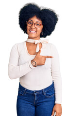 Canvas Print - Young african american girl wearing casual clothes and glasses cheerful with a smile on face pointing with hand and finger up to the side with happy and natural expression