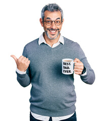 Canvas Print - Middle age hispanic man with grey hair drinking mug of coffee with best dad ever message pointing thumb up to the side smiling happy with open mouth