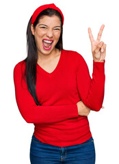 Poster - Young hispanic woman wearing casual clothes smiling with happy face winking at the camera doing victory sign. number two.