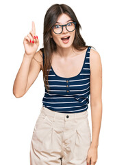 Canvas Print - Young beautiful caucasian girl wearing casual clothes and glasses pointing finger up with successful idea. exited and happy. number one.